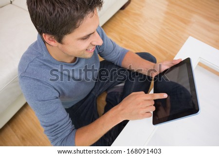 Overhead view of a young man using digital tablet in living room at home