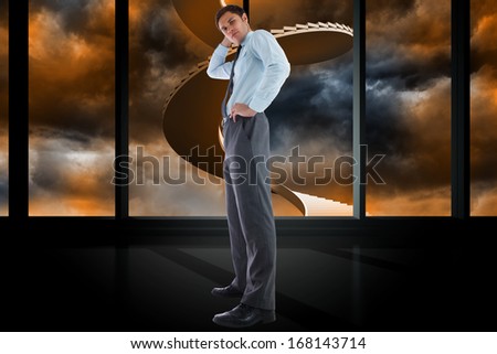 Thinking businessman with hand on head against winding staircase in orange sky
