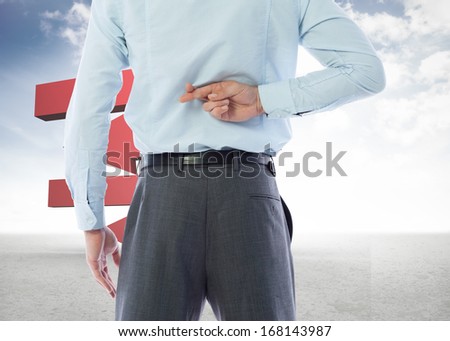 Businessman crossing fingers behind his back against red arrows in a desert landscape