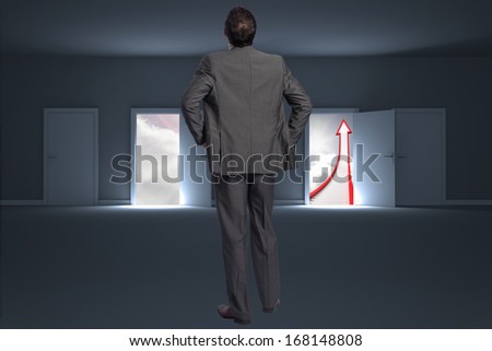 Businessman with hands on hips against doors opening to show red arrow and sky