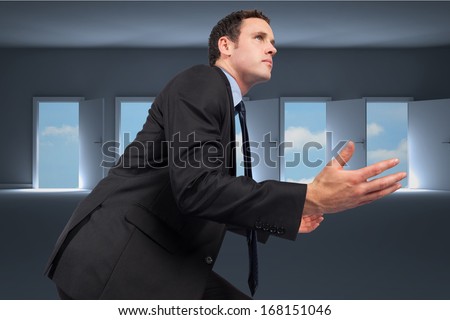 Businessman posing with arms out against doors opening in dark room to show sky