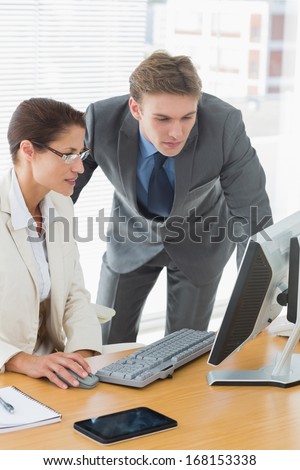 Smartly dressed business couple using computer at office desk