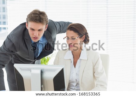 Smartly dressed business couple using computer in a bright office