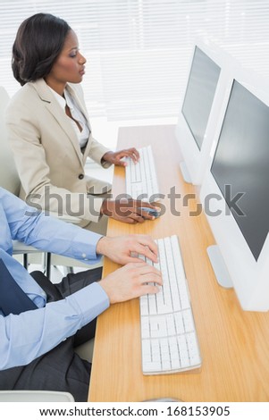 Side view of business colleagues using computers at office desk