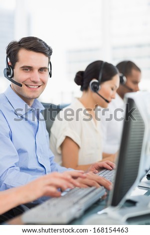 Side view portrait of business colleagues with headsets using computers at office
