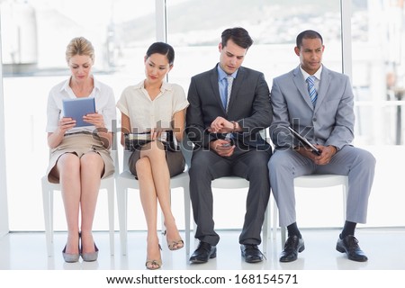 Full length of business people waiting for job interview in a bright office