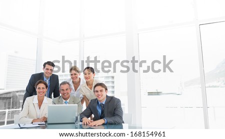 Group of happy business colleagues with laptop at office desk