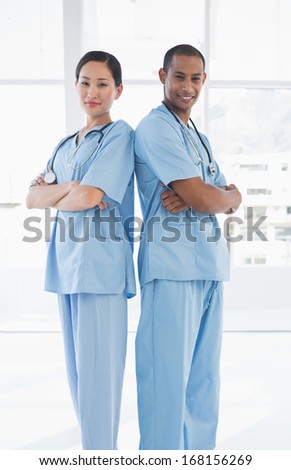 Portrait of two confident surgeons standing back to back in the hospital