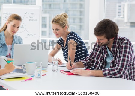 Young casual business people sitting around conference table in a bright office