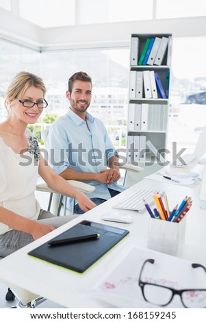 Side view portrait of smiling casual young couple with computer in a bright office