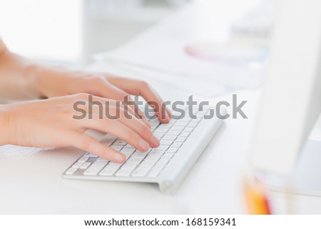Close-up side view of hands using computer keyboard in a bright office