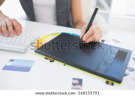 Close-up mid section of a female photo editor using graphics tablet in a bright office