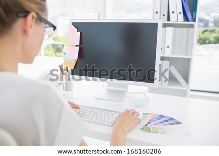 Rear view of photo editor working on computer in a bright office