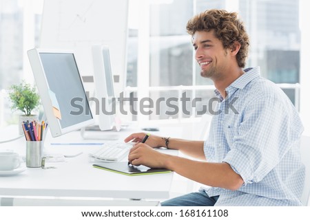 Side view of a male artist drawing something on graphic tablet with pen