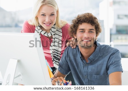 Portrait of a smiling casual business couple using computer in a bright office