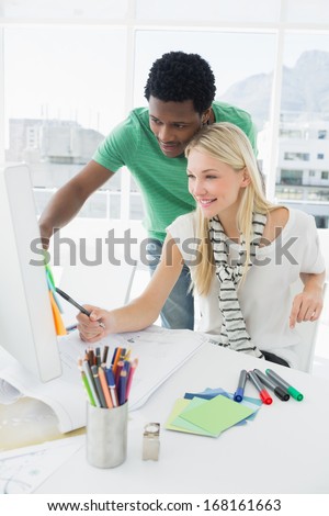 Smiling young casual couple using computer in a bright office