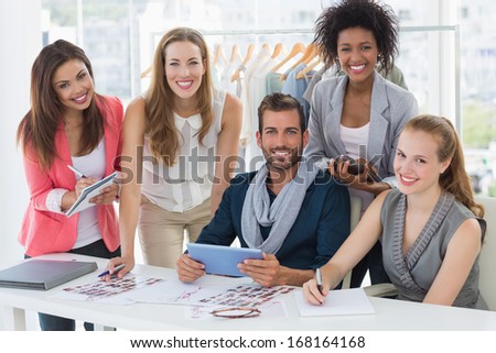 Group portrait of fashion designers discussing designs in a studio