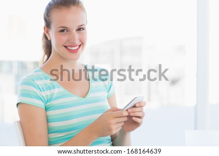 Portrait of a beautiful young casual woman text massaging at a bright office