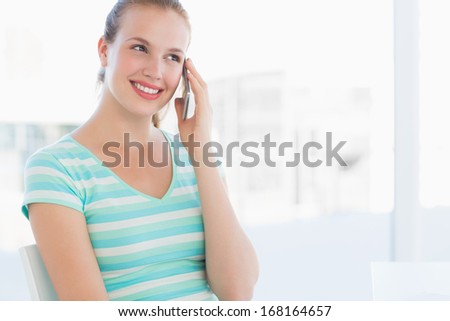 Beautiful young casual woman using mobile phone at a bright office