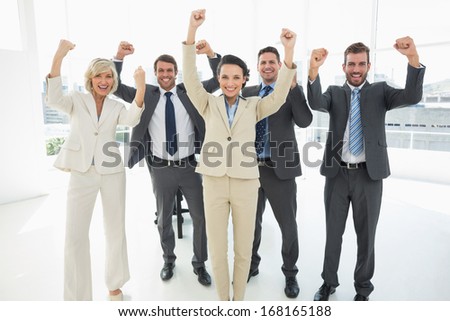 Portrait of a successful business team clenching fists in a bright office