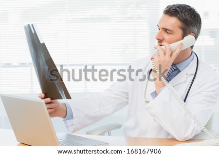 Serious male doctor examining x-ray while on call in the medical office
