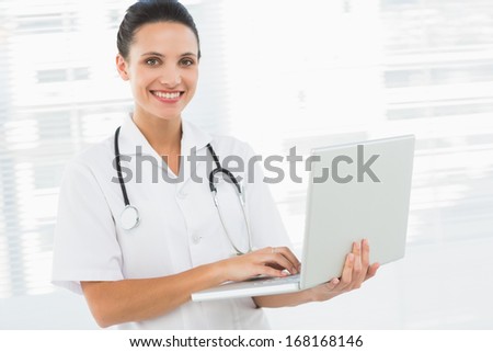 Portrait of a smiling young female doctor using laptop in the medical office