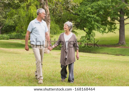 Full length of a happy senior couple holding hands and walking in the park
