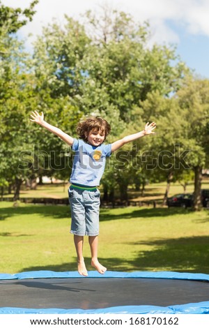 Full length of a happy boy jumping high on trampoline in the park