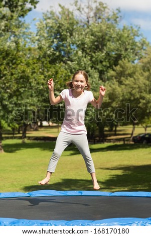 Full length of a happy girl jumping high on trampoline in the park