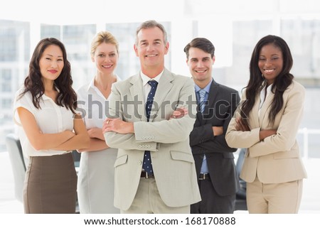 Business team smiling at camera with arms folded in the office
