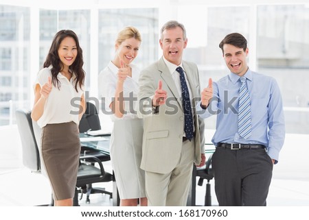 Business team giving thumbs up to the camera in the office