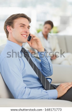 Happy businessman on the phone sitting on sofa in the office