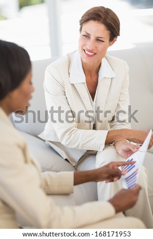 Happy businesswomen meeting to go over charts on the couch in the office