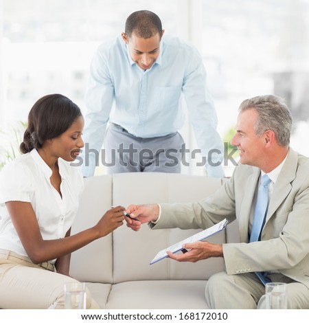 Salesman handing pen to client to sign the contract in the office