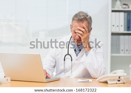 Stressed doctor sitting at his desk in his office at the hospital