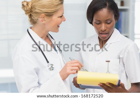 Smiling doctor and nurse going over file together in an office at the hospital