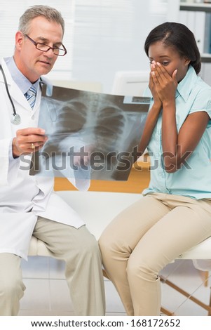 Doctor showing pleased patient her positive chest xray in his office at the hospital