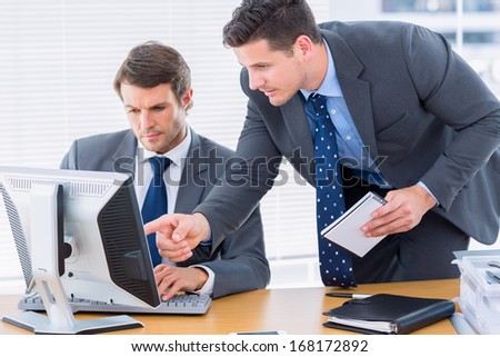 Smartly dressed young businessmen using computer at office desk