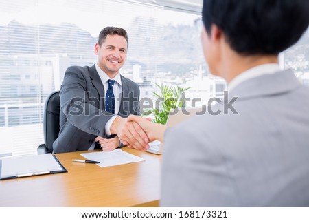 Smartly dressed executives shaking hands after a business meeting in the office