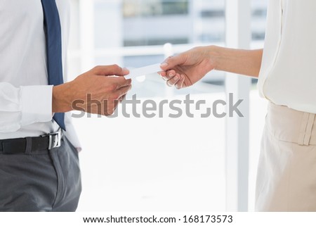Side view mid section of two executives exchanging business card