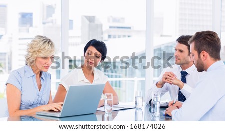 Smartly dressed young executives sitting around conference table in office