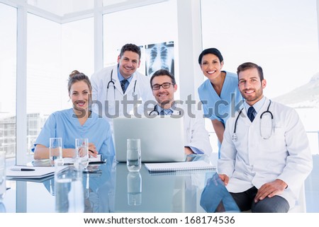 Portrait of a happy medical team using laptop together in the office