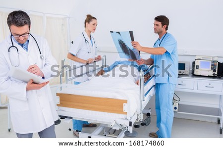 Doctors holding reports by patient in bed at the hospital