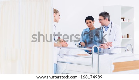 Doctors showing x-ray to female patient in bed at the hospital