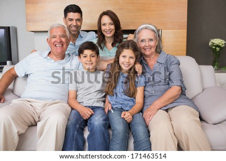 Portrait of smiling extended family sitting on sofa in the living room at home