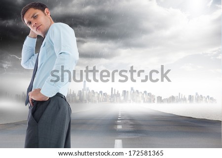 Thinking businessman with hand on head against open road