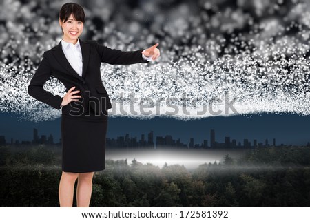 Smiling businesswoman pointing against bright stars of energy over landscape