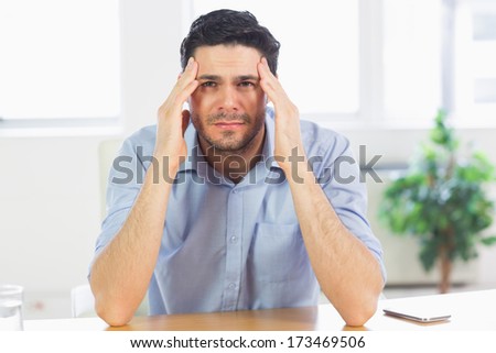 Portrait of businessman suffering from headache at office desk