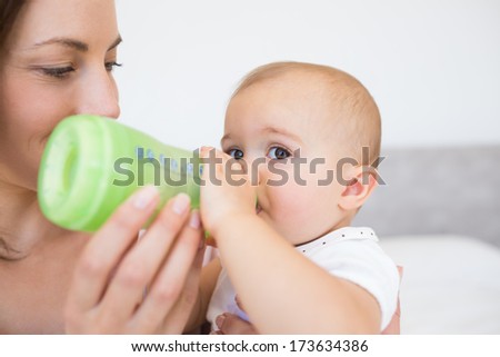 Closeup of a mother feeding baby with milk bottle at home