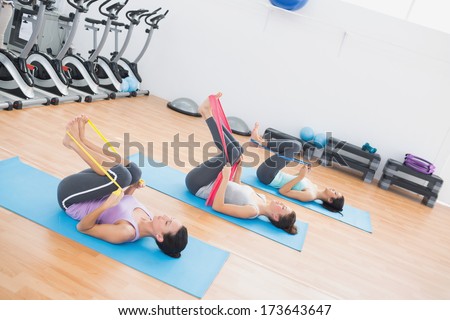 Full length side view of sporty young women with exercise bands in the fitness studio